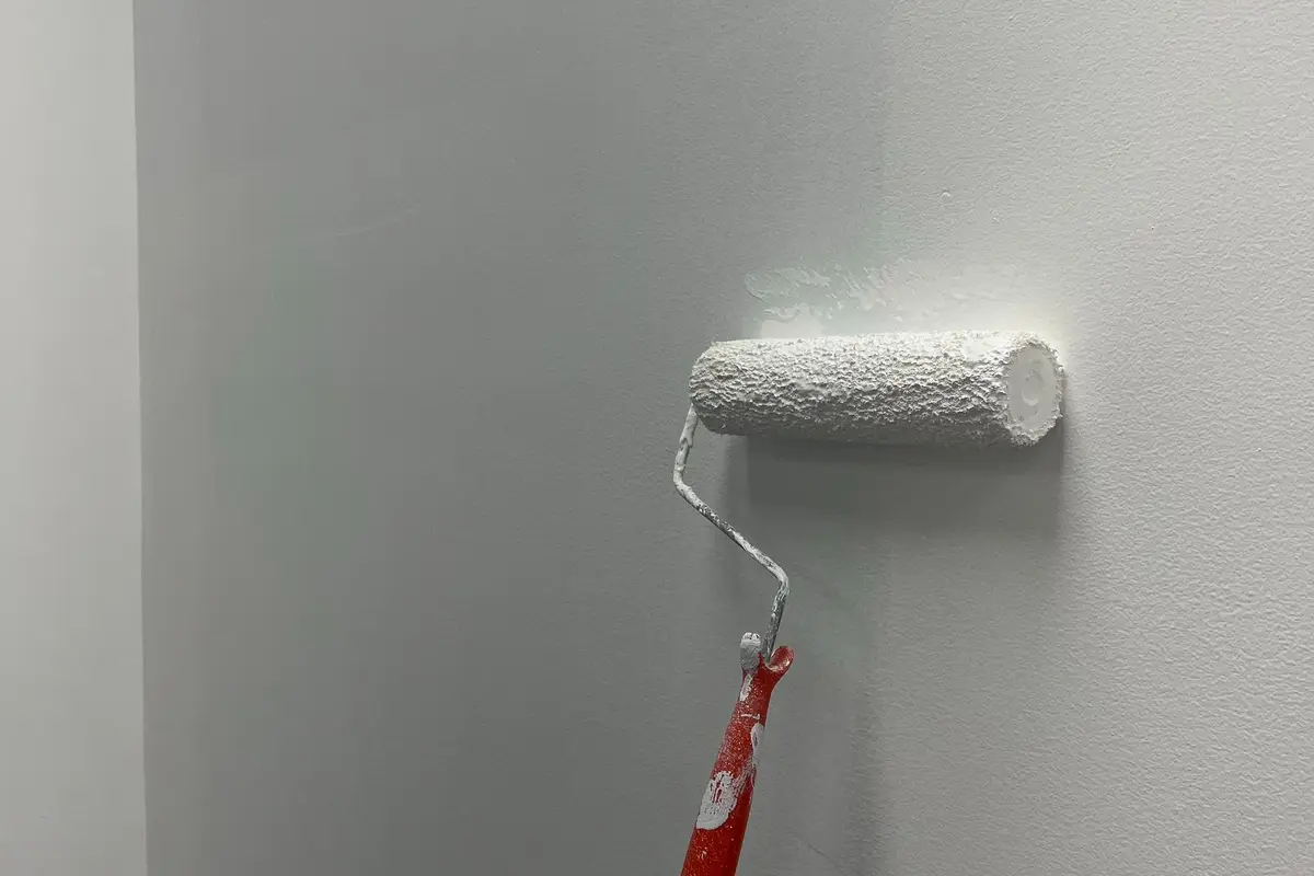 Rodillo aplicando pintura blanca en una pared